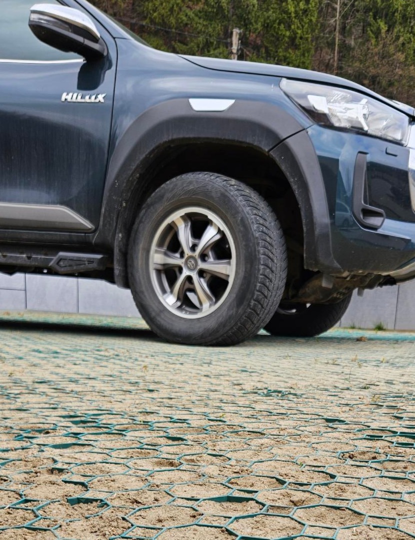 Zelená zatrávňovacia dlažba Multigravel pod kolesami SUV vozidla na spevnenom parkovisku