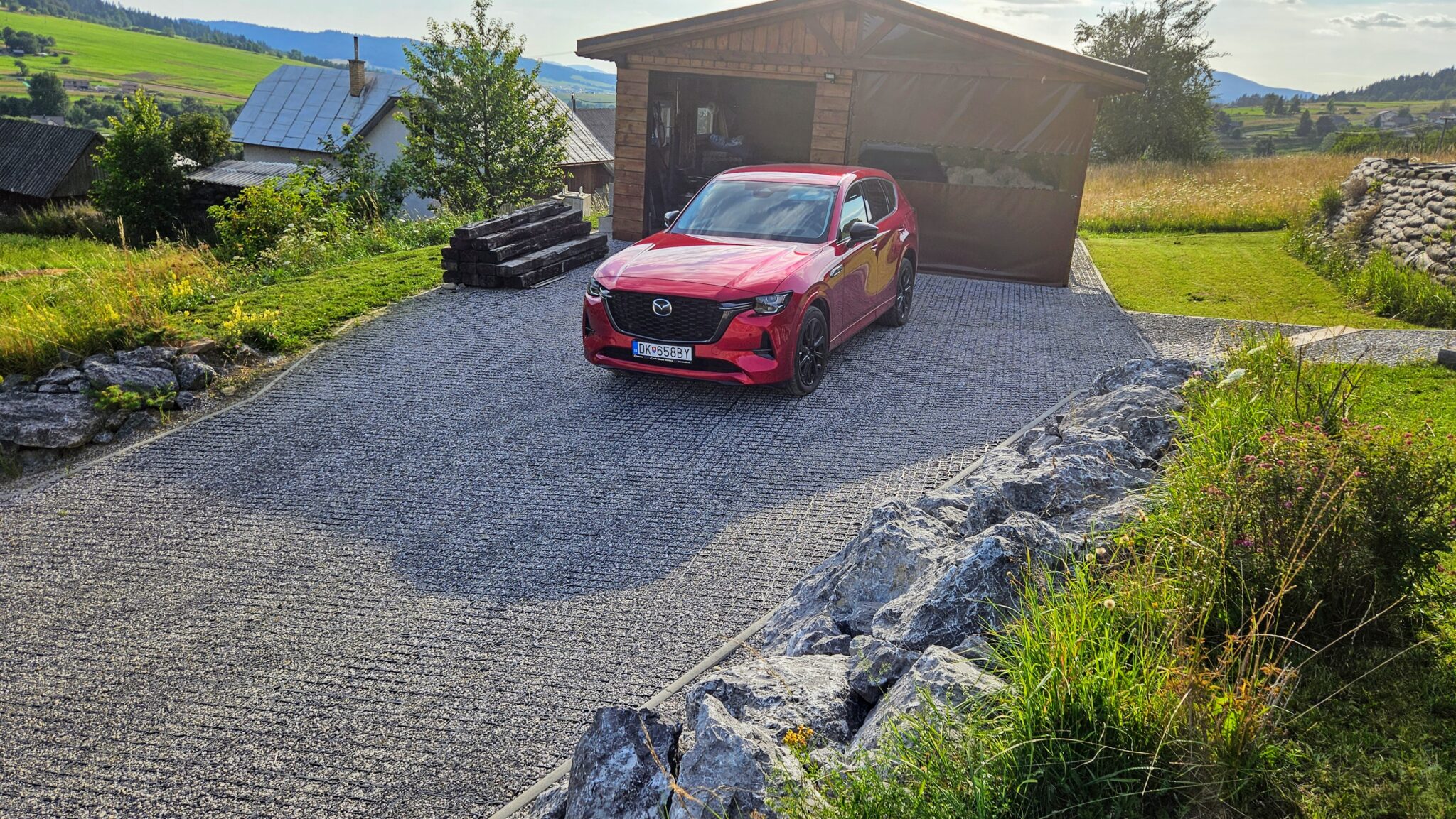 Parkovisko zo štrku spevnené plastovými zatrávňovačmi s červeným autom