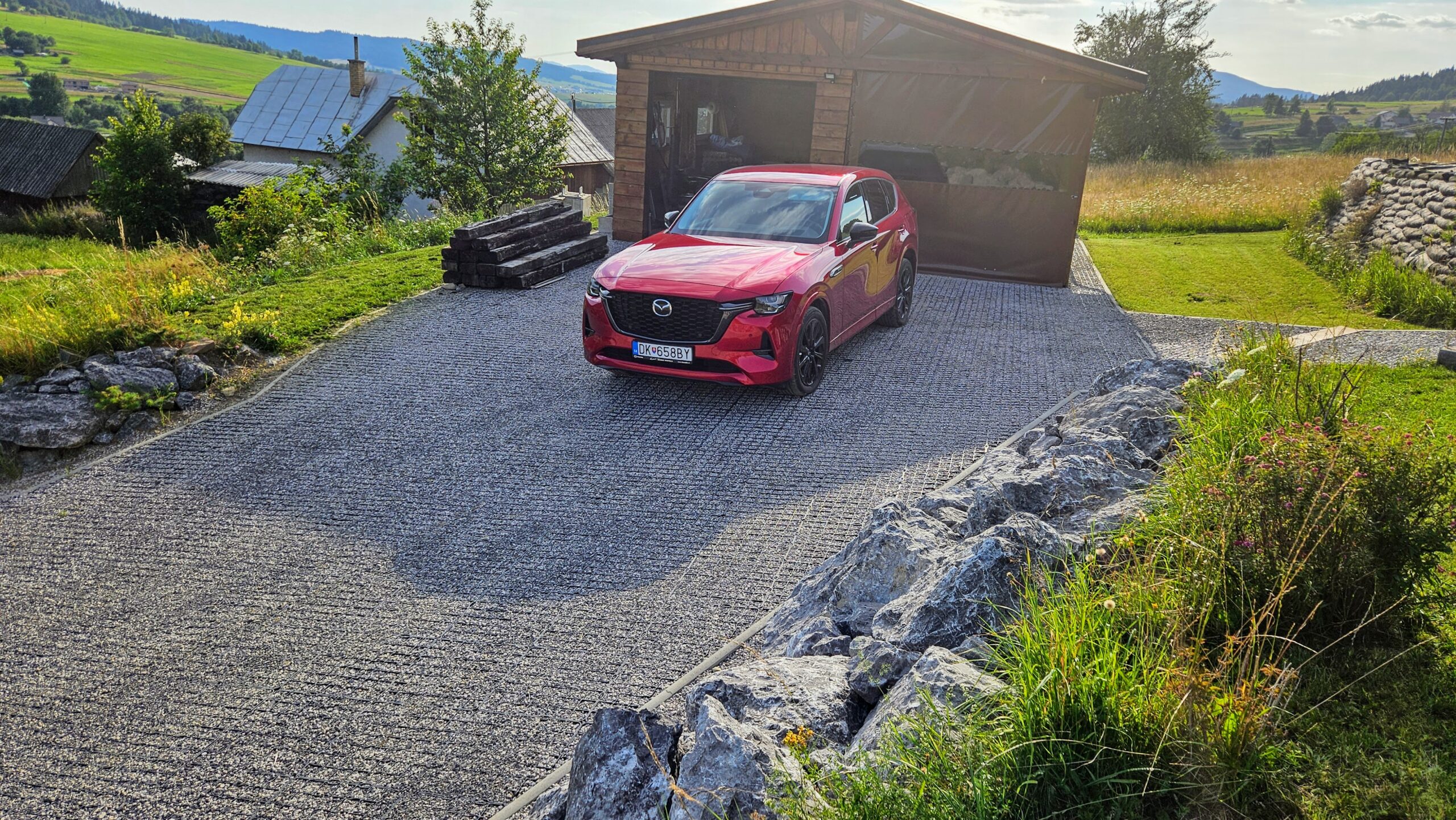 Parkovisko zo štrku spevnené plastovými zatrávňovačmi s červeným autom